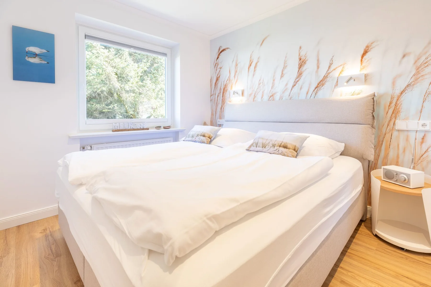 A bright bedroom with a large bed and a window overlooking greenery.
