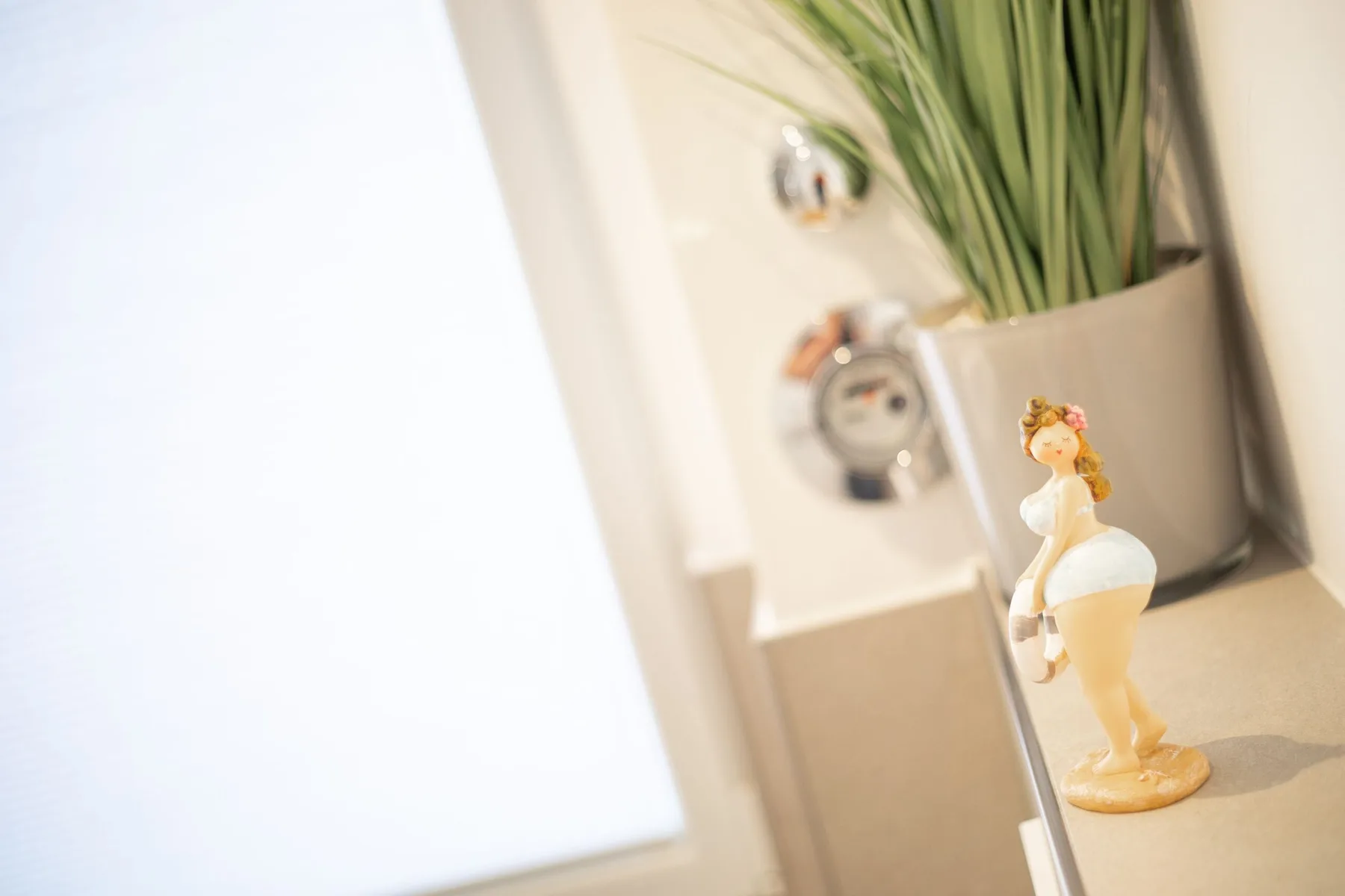 A bathroom vanity holds a decorative figurine beside a potted plant.