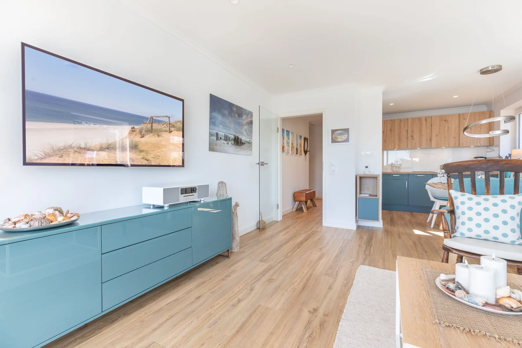 A bright living and dining area opens onto a kitchen with wood cabinetry.