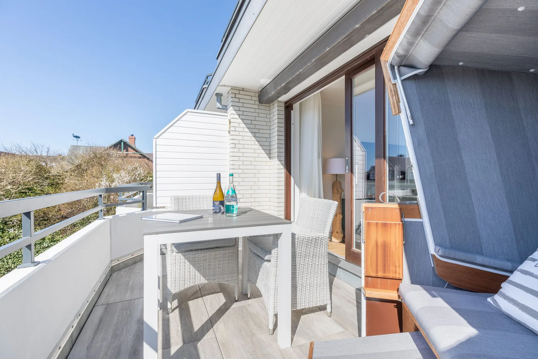 A balcony with a table and seating beside a sliding glass door.