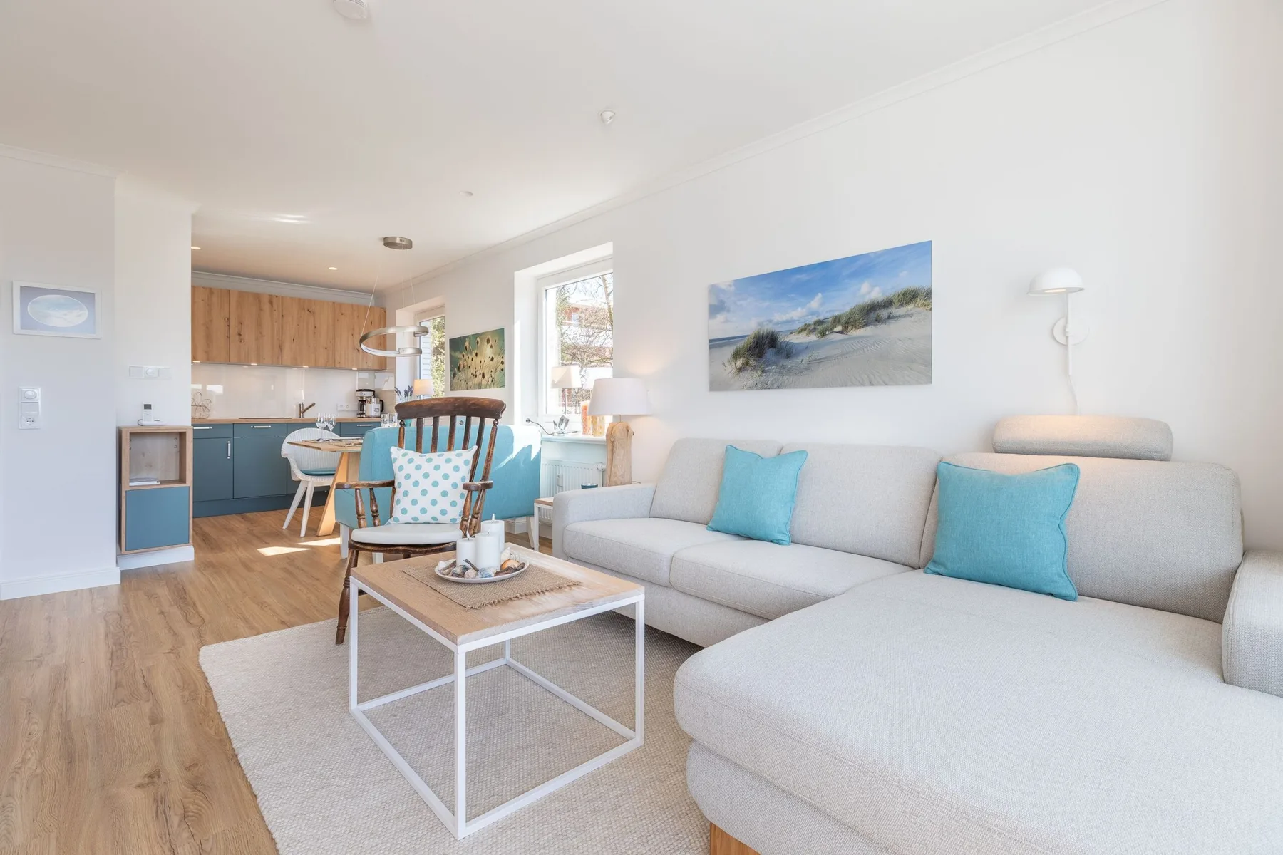 A bright living room with a sectional seating area and an open kitchen.