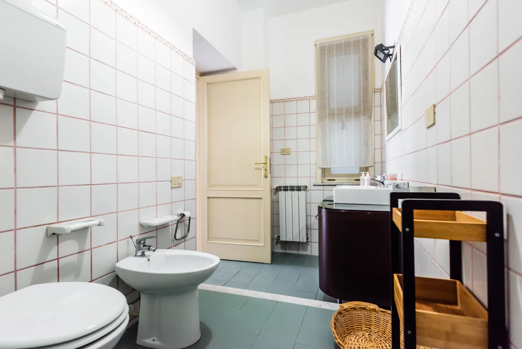A tiled bathroom with a toilet, sink, and open door.