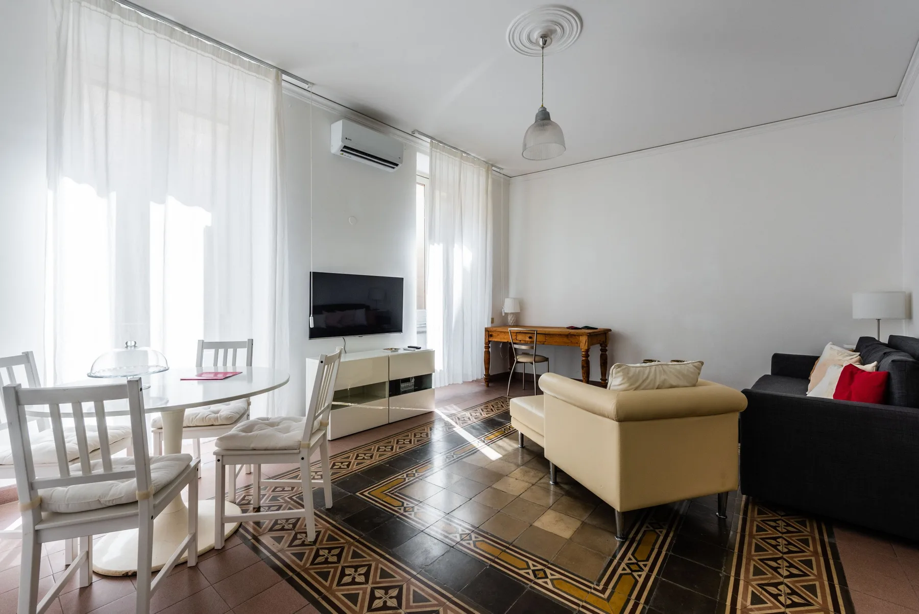 A bright living room with a dining table, television, and seating.