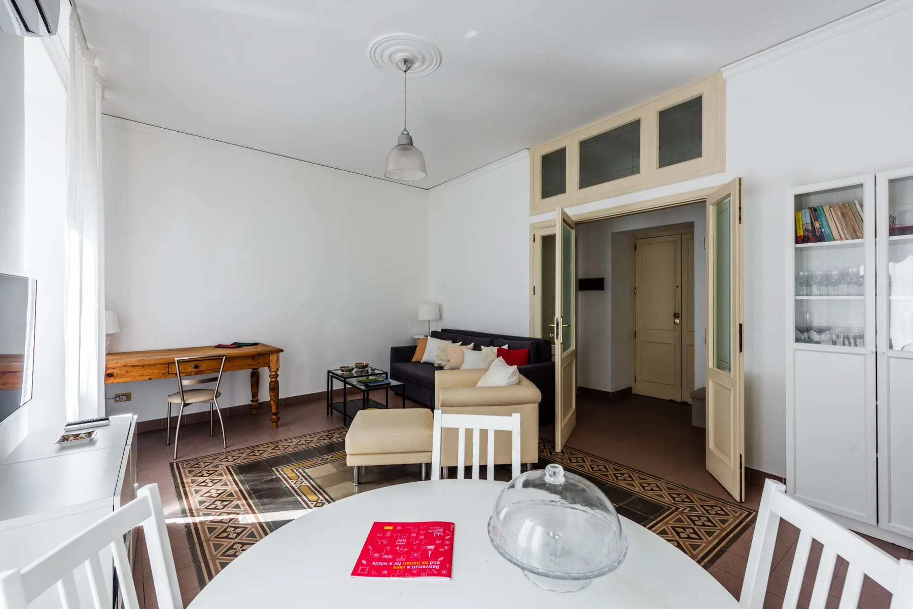 A bright living room with seating around a table and a patterned rug.