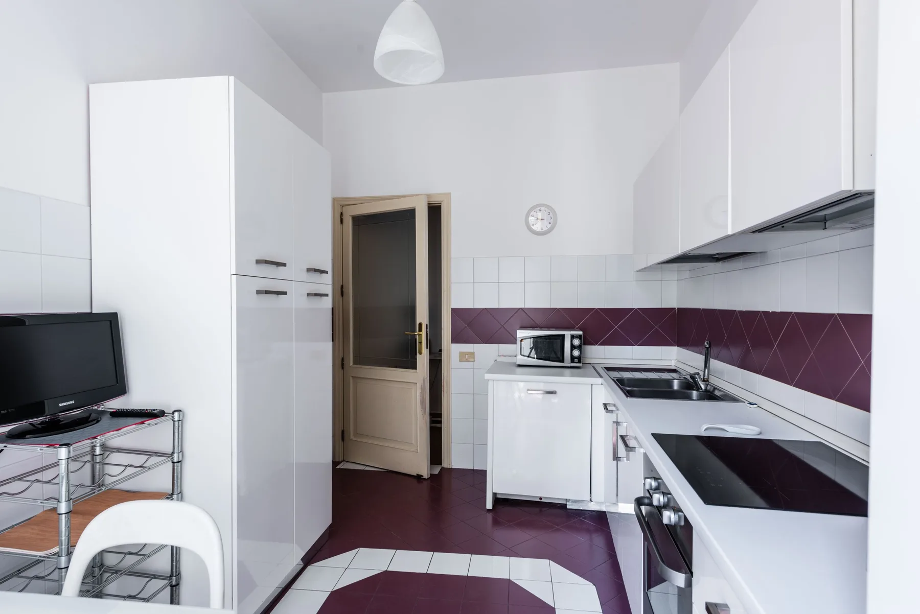 A bright kitchen with white cabinets, a countertop, and a small dining area.