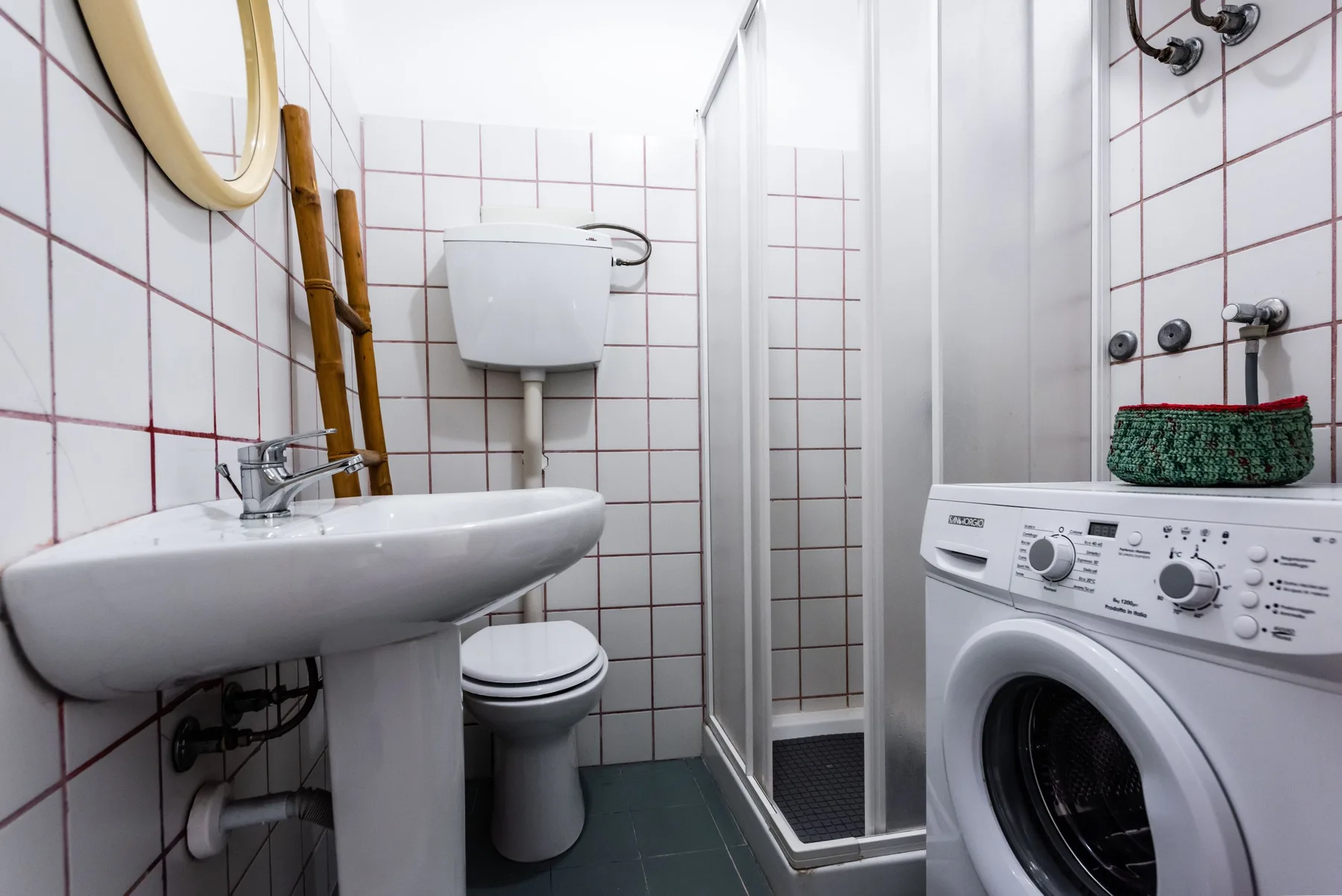 A compact bathroom with a sink, toilet, shower, and washing machine.