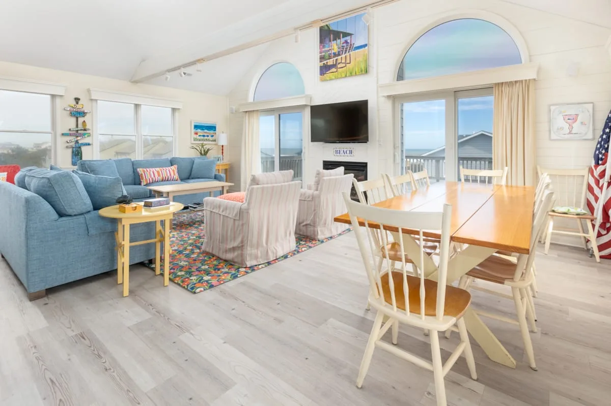 A bright living and dining area with blue seating and a wooden dining table.