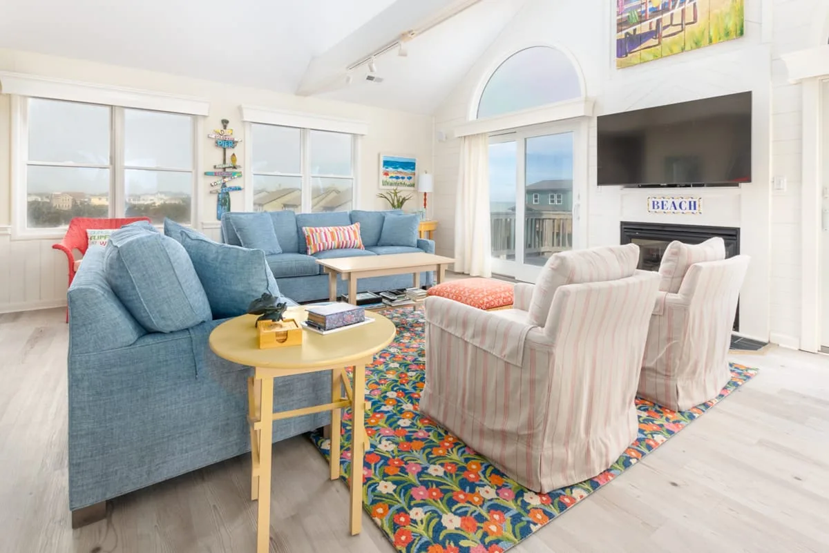 A bright living room with blue seating, armchairs, and a television.