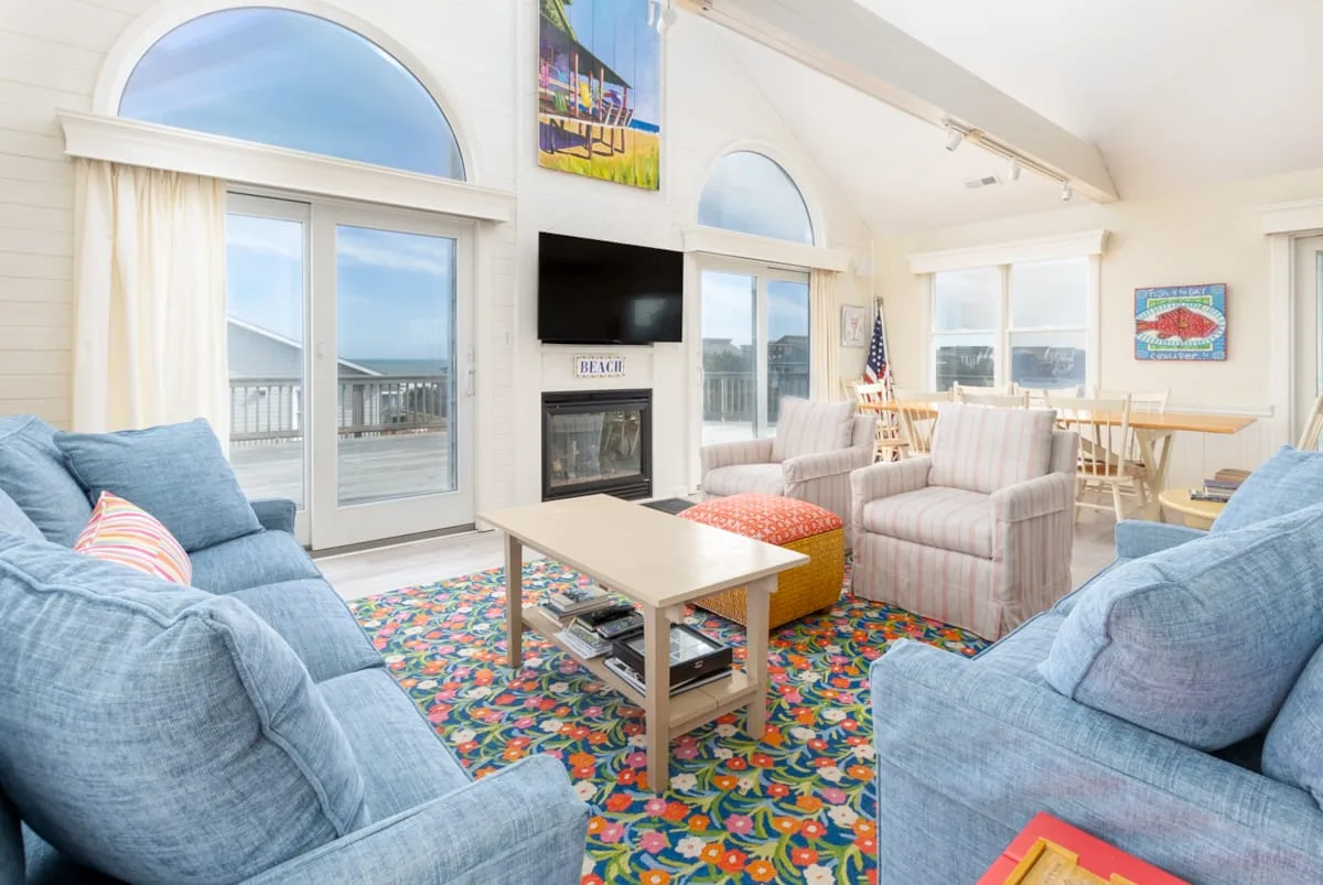 A bright living room with blue seating, a coffee table, and large windows.