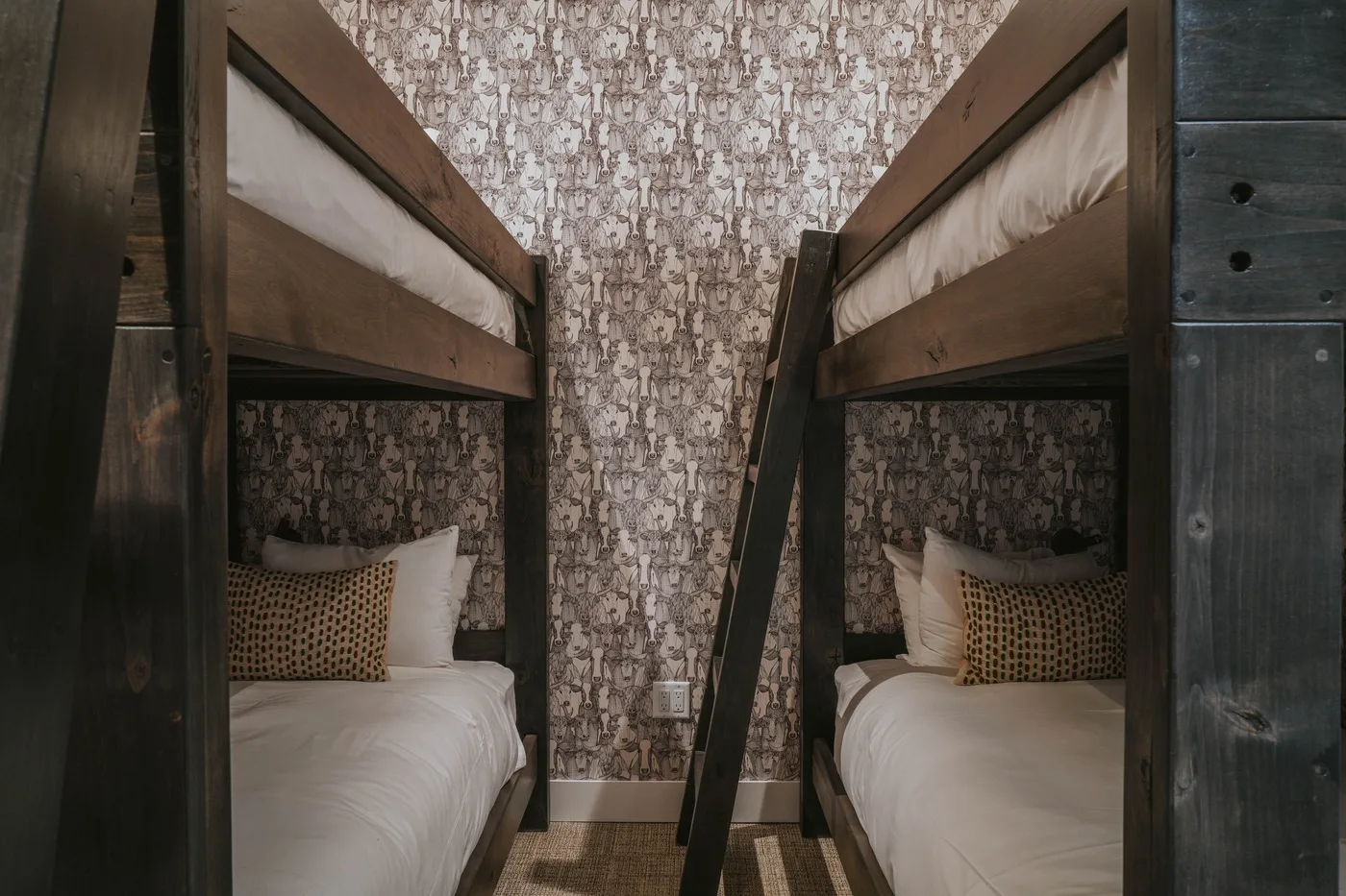 A compact bunk bedroom with two lower beds facing a patterned wall.