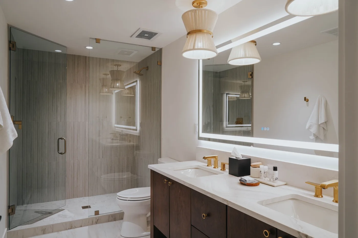 A modern bathroom with a long vanity, mirrors, and a glass shower.