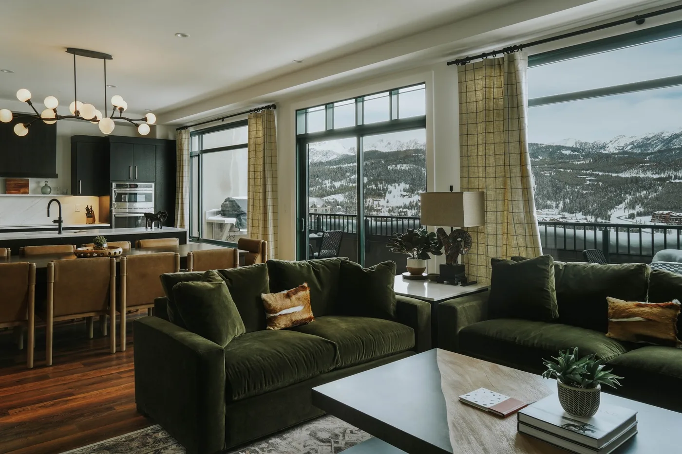 A living room with seating and large windows overlooking a snowy mountain view.