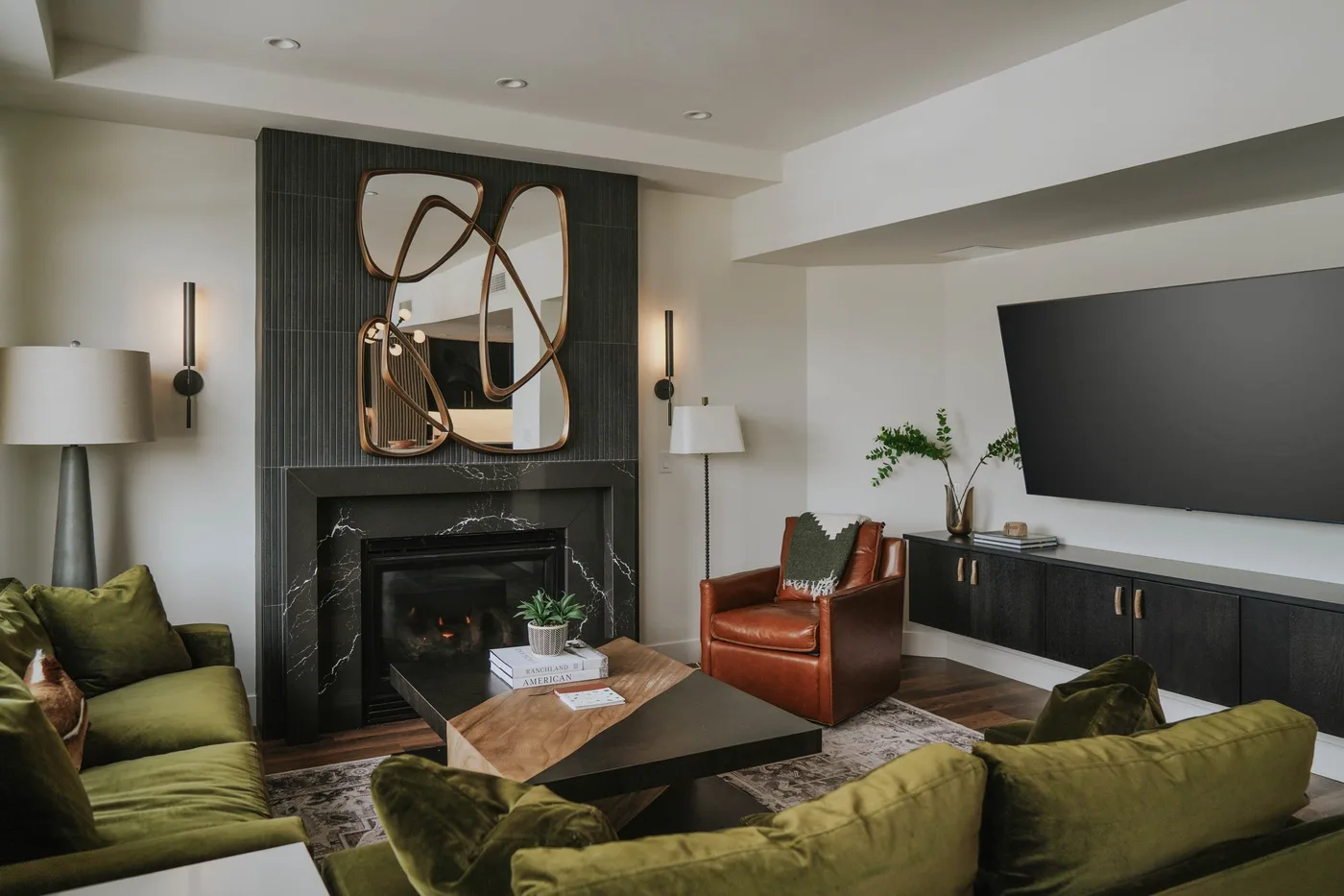 A modern living room with green seating, a fireplace, and a television.