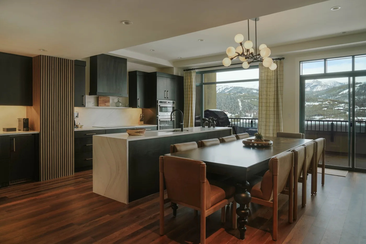An open-plan kitchen and dining area with large windows overlooking a mountain view.
