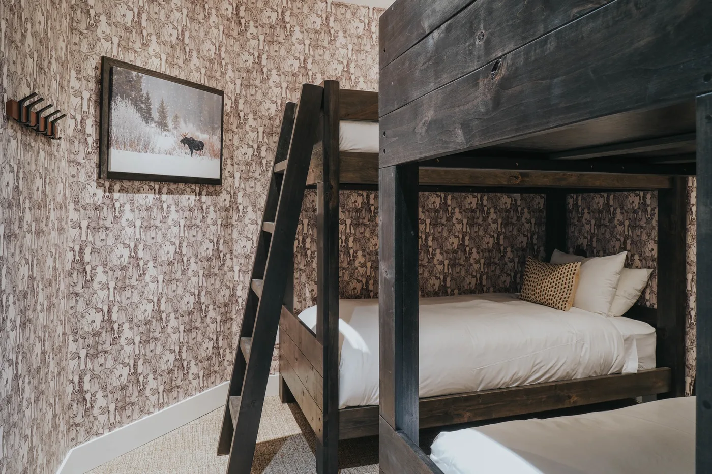 A bedroom with a dark wooden bunk bed and patterned wallpaper.
