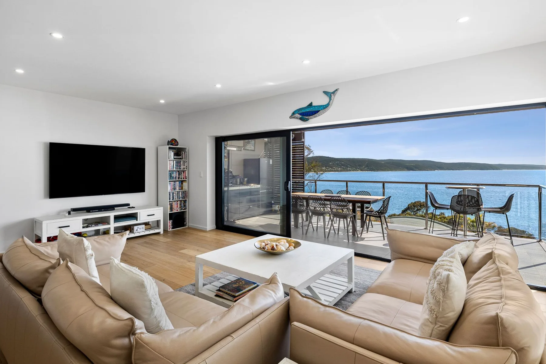A bright living room opens onto a balcony overlooking the water.