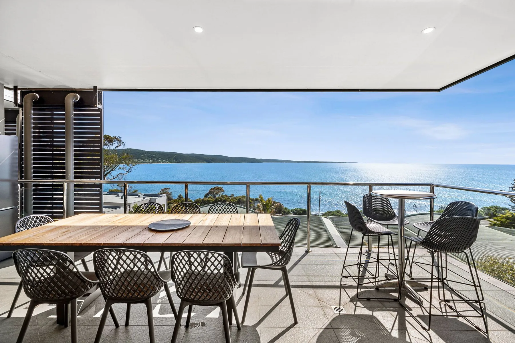 An outdoor dining area overlooks the ocean, with a table and seating.