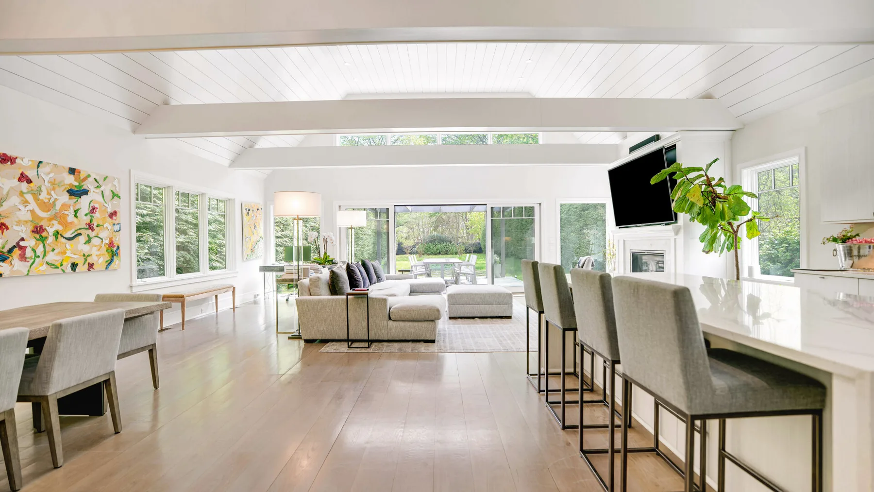 A bright open-plan living and dining area with large windows and a central seating area.