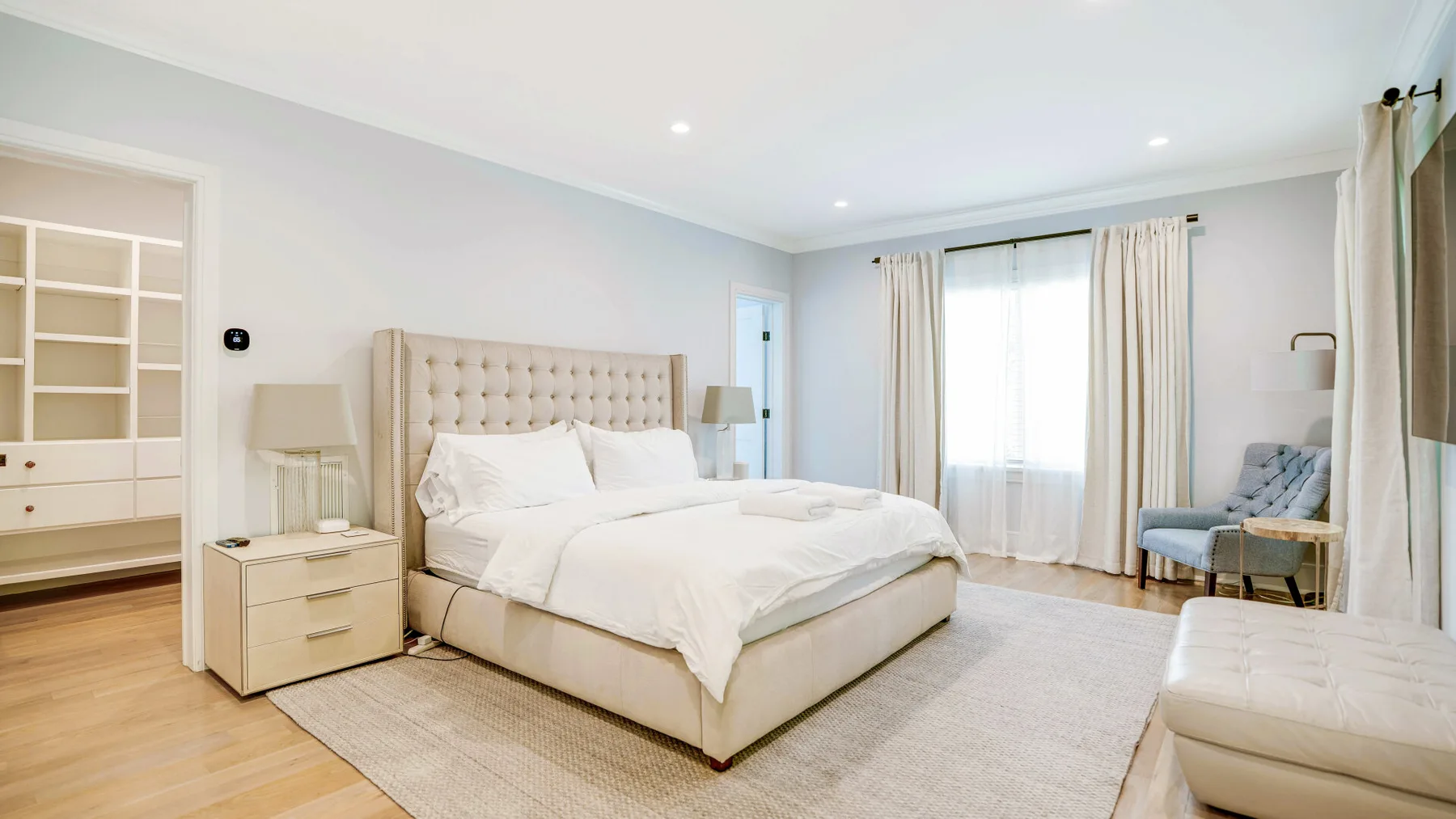A bright bedroom with a large bed and a seating area by the window.
