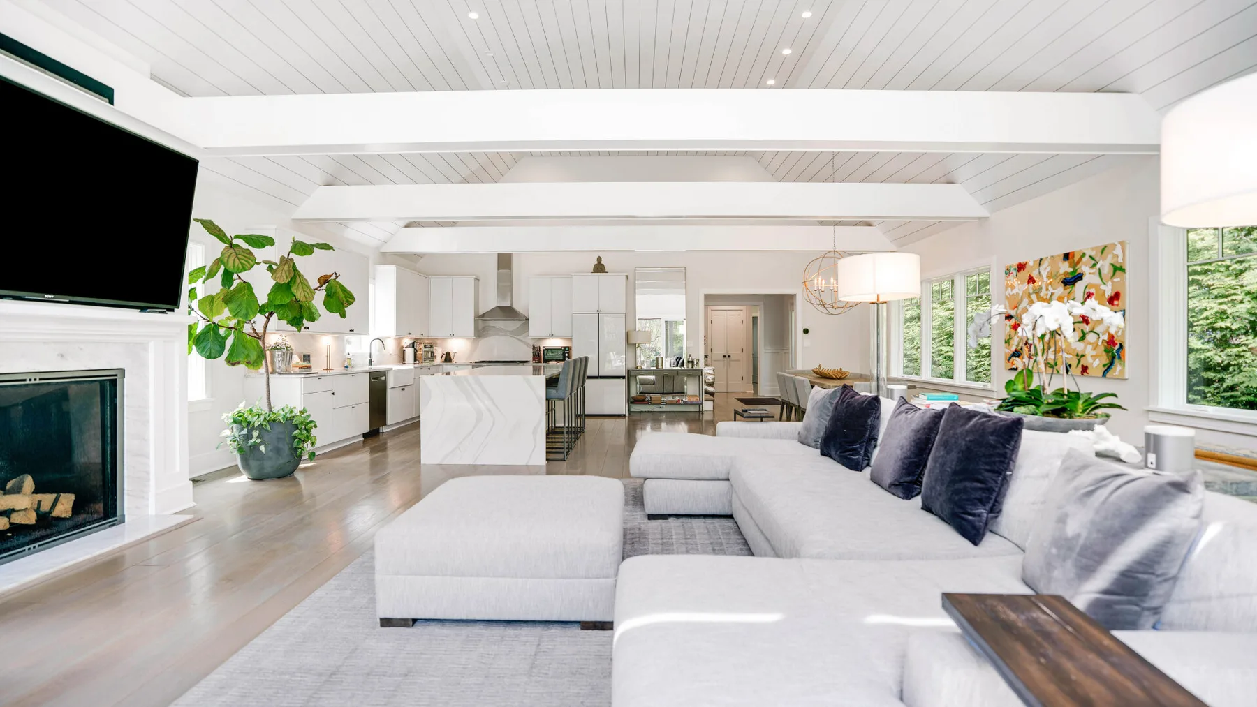 A bright open-plan living room with a sectional seating area and kitchen.