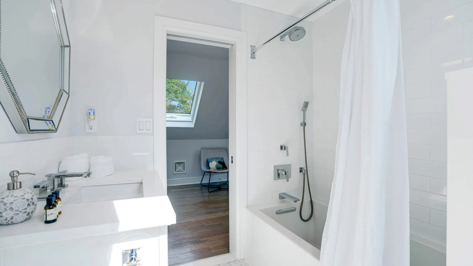 A bright bathroom with a sink and a shower beside an open doorway.