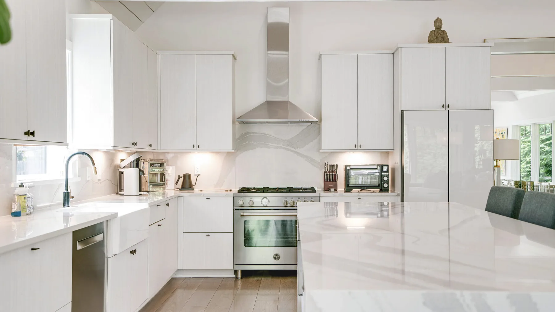 A bright kitchen with white cabinets, a stove, and a large island.