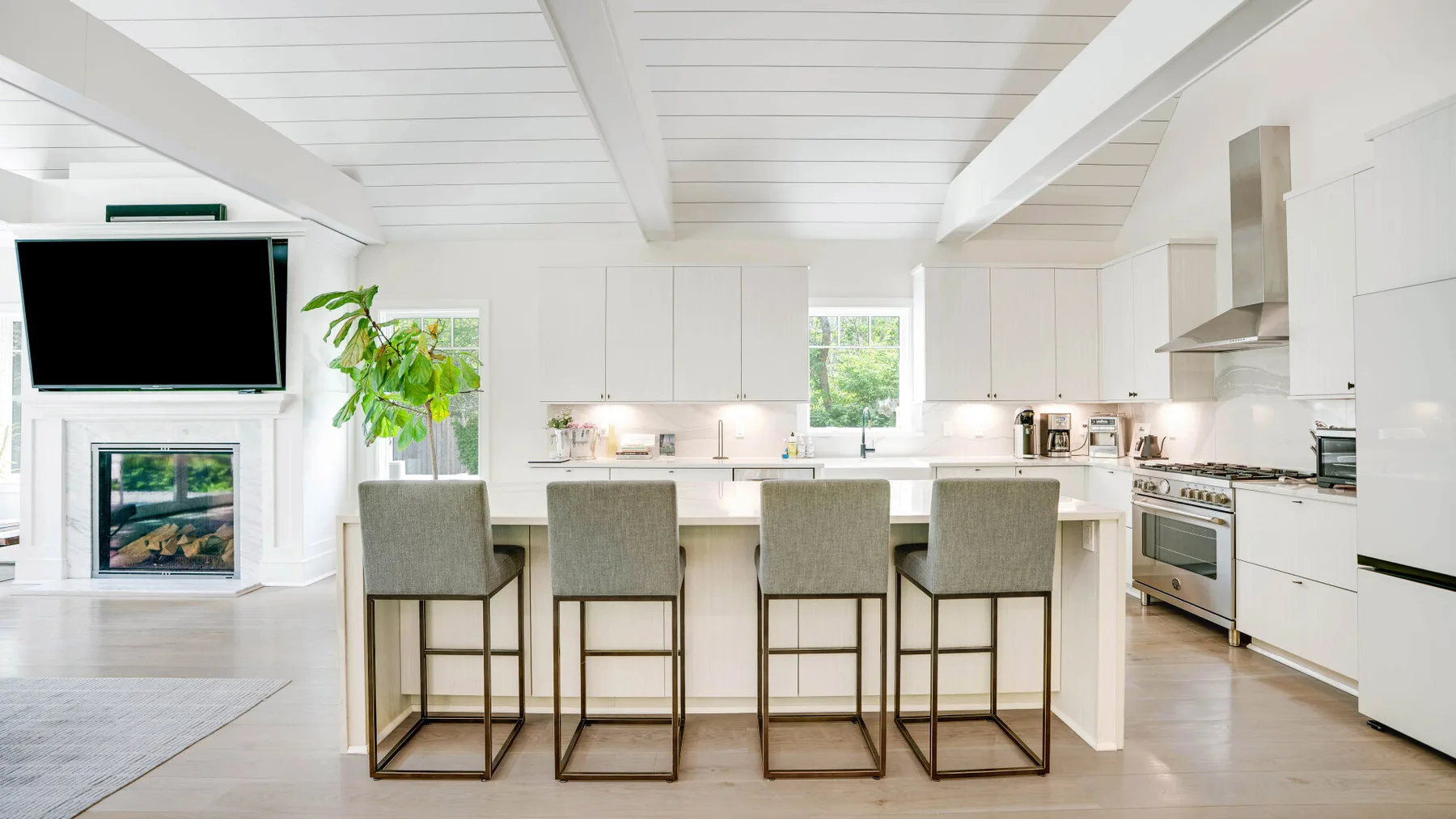 A bright kitchen with a central island and bar seating beneath a high white ceiling.