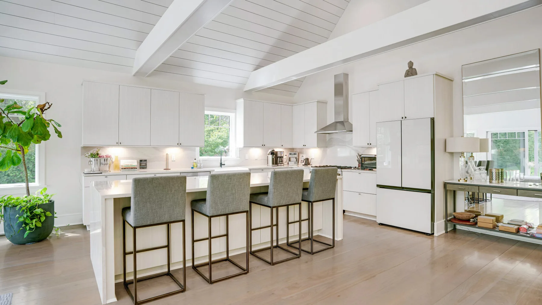 A bright kitchen with a large island and bar seating beneath a vaulted ceiling.