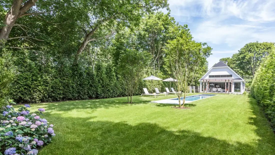 A spacious lawn with garden seating and a glass-fronted pavilion.