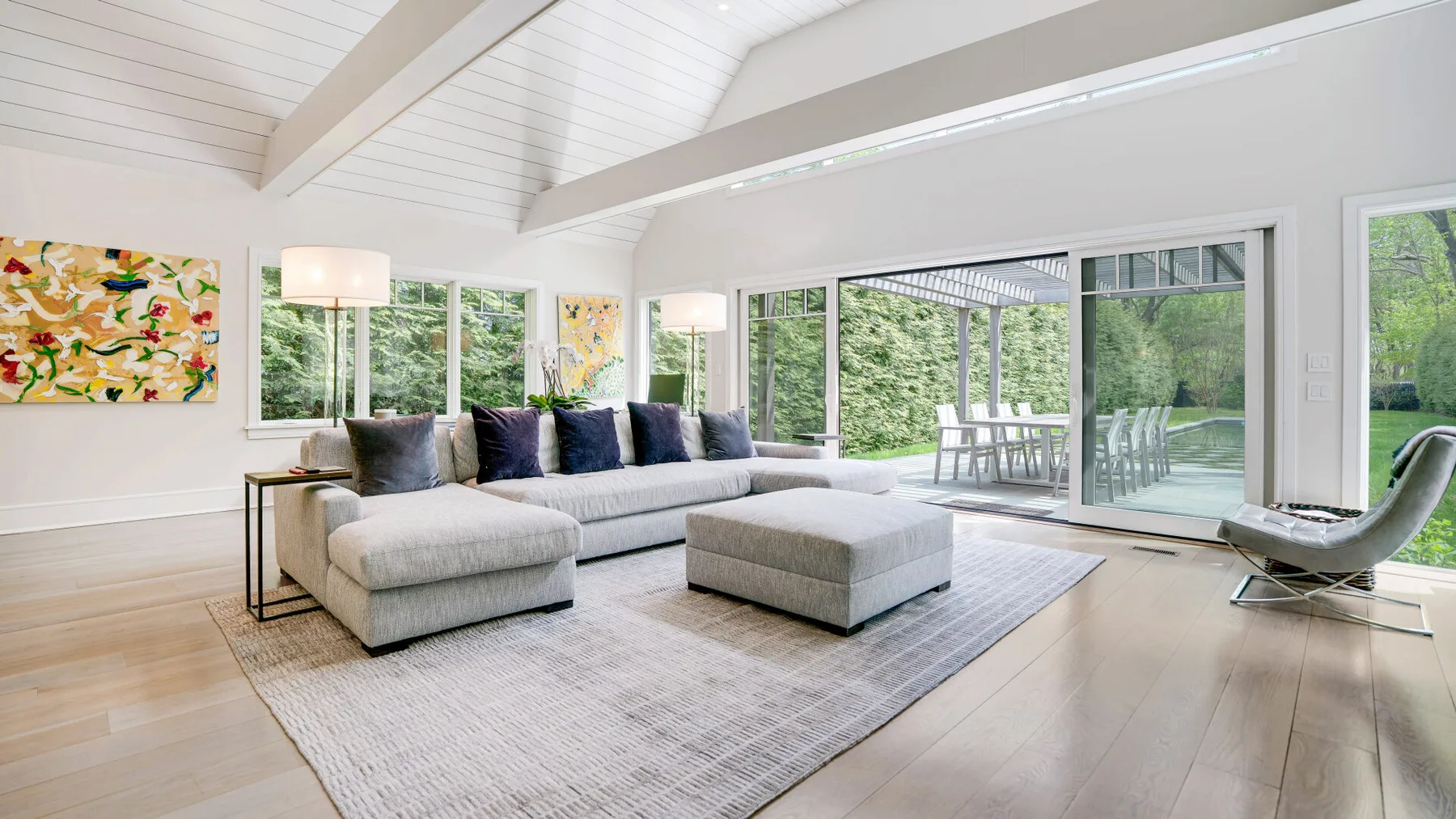 A bright living room with a sectional seating area and large windows overlooking greenery.