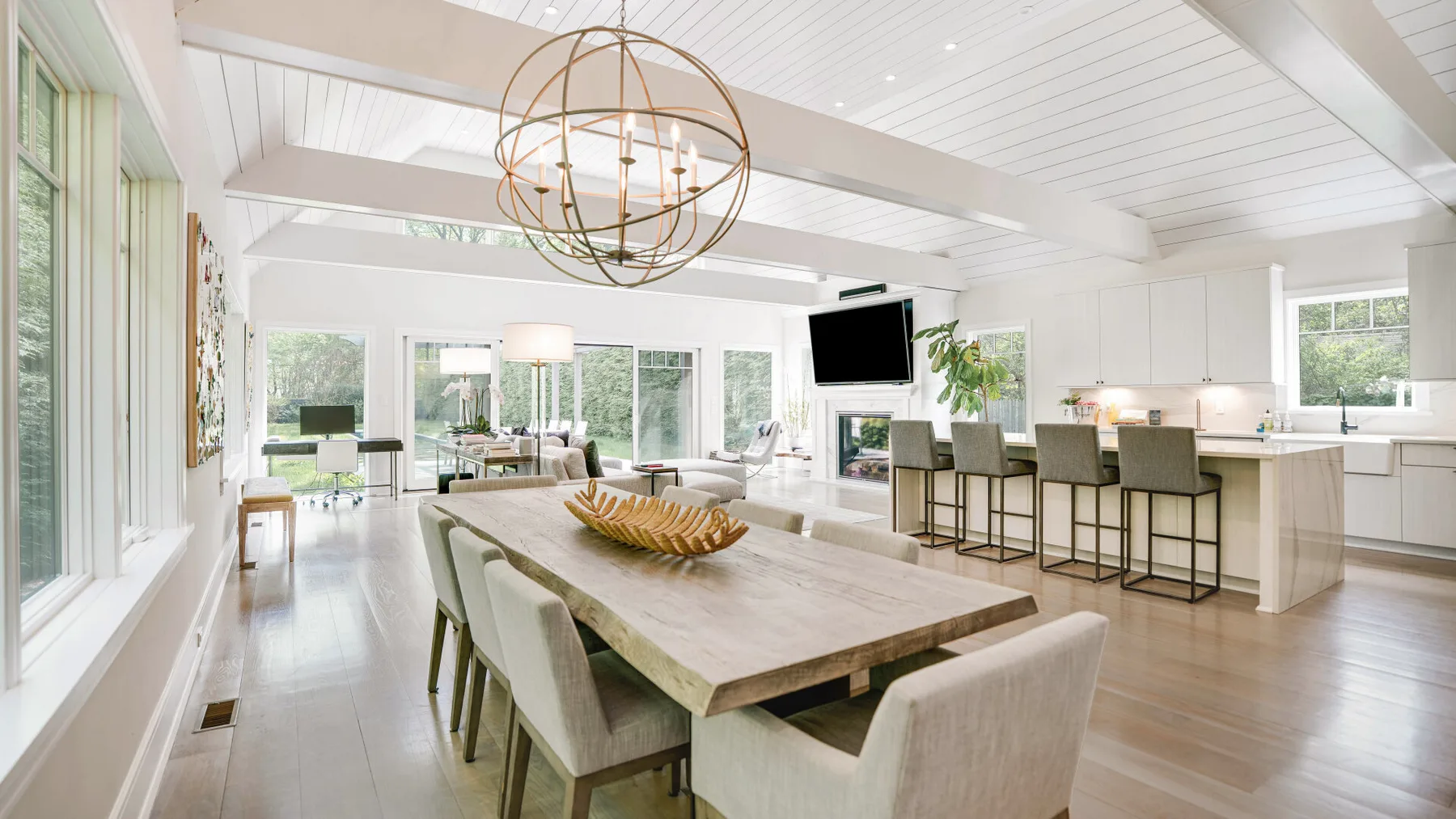 A bright open-plan dining and kitchen area with a large table and bar seating.