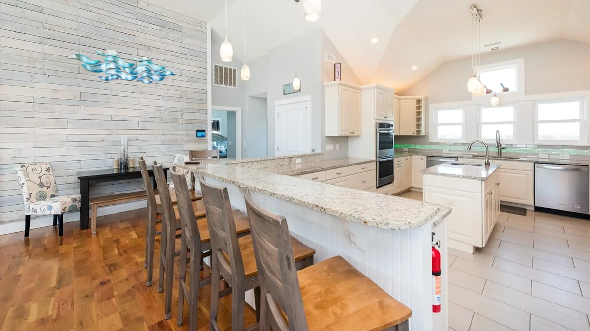 Una cocina y comedor luminosos con una barra larga y una mesa de comedor de madera.
