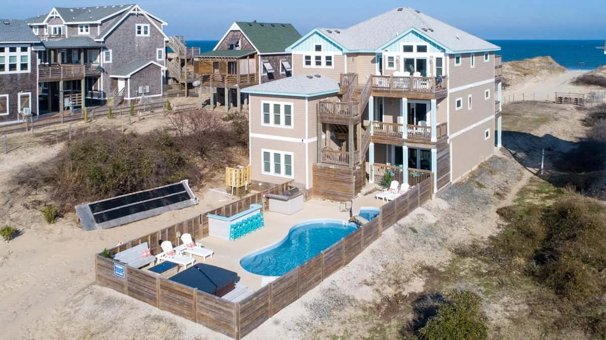 Una casa costera da a una piscina cercada y una terraza.