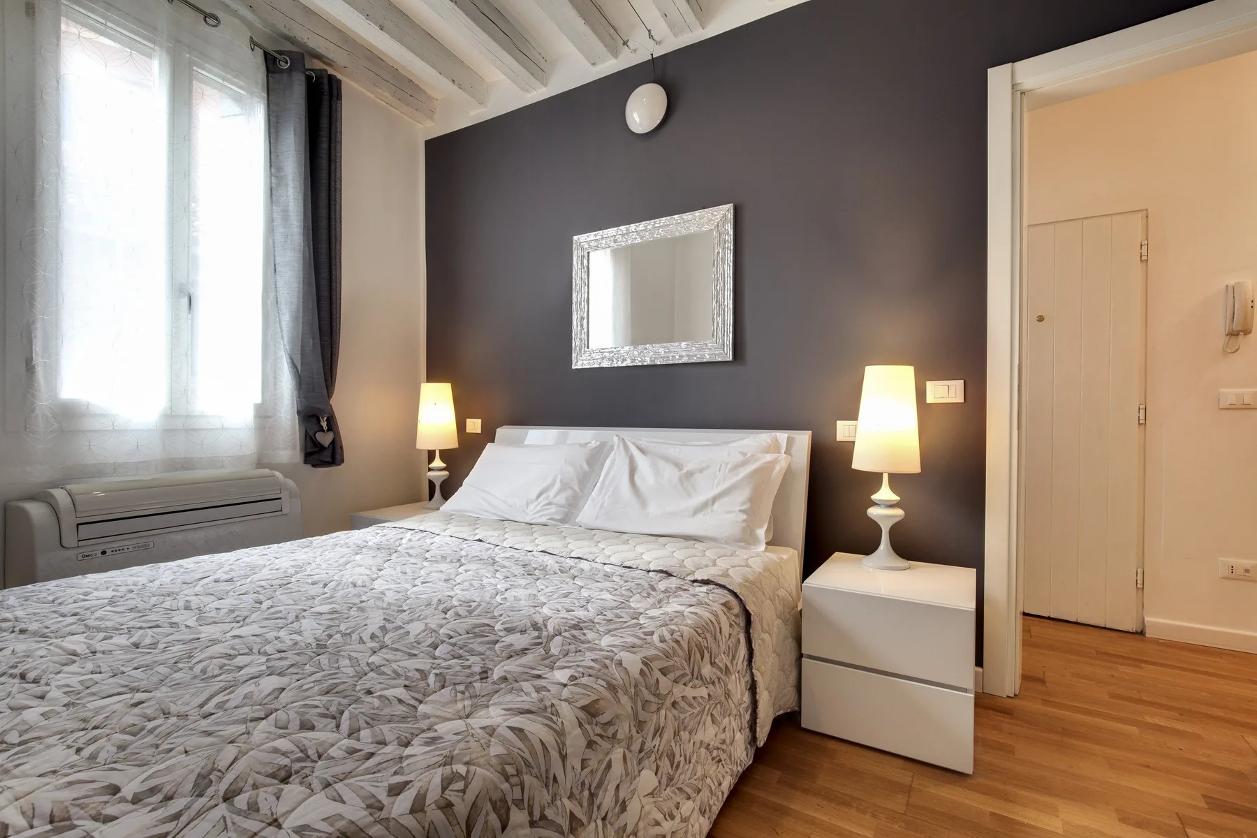 A bedroom with a bed, bedside tables, and a mirror on the wall.