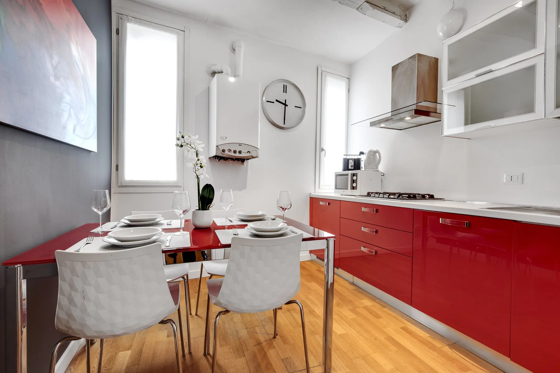 A bright kitchen and dining area with red cabinets and a set table.