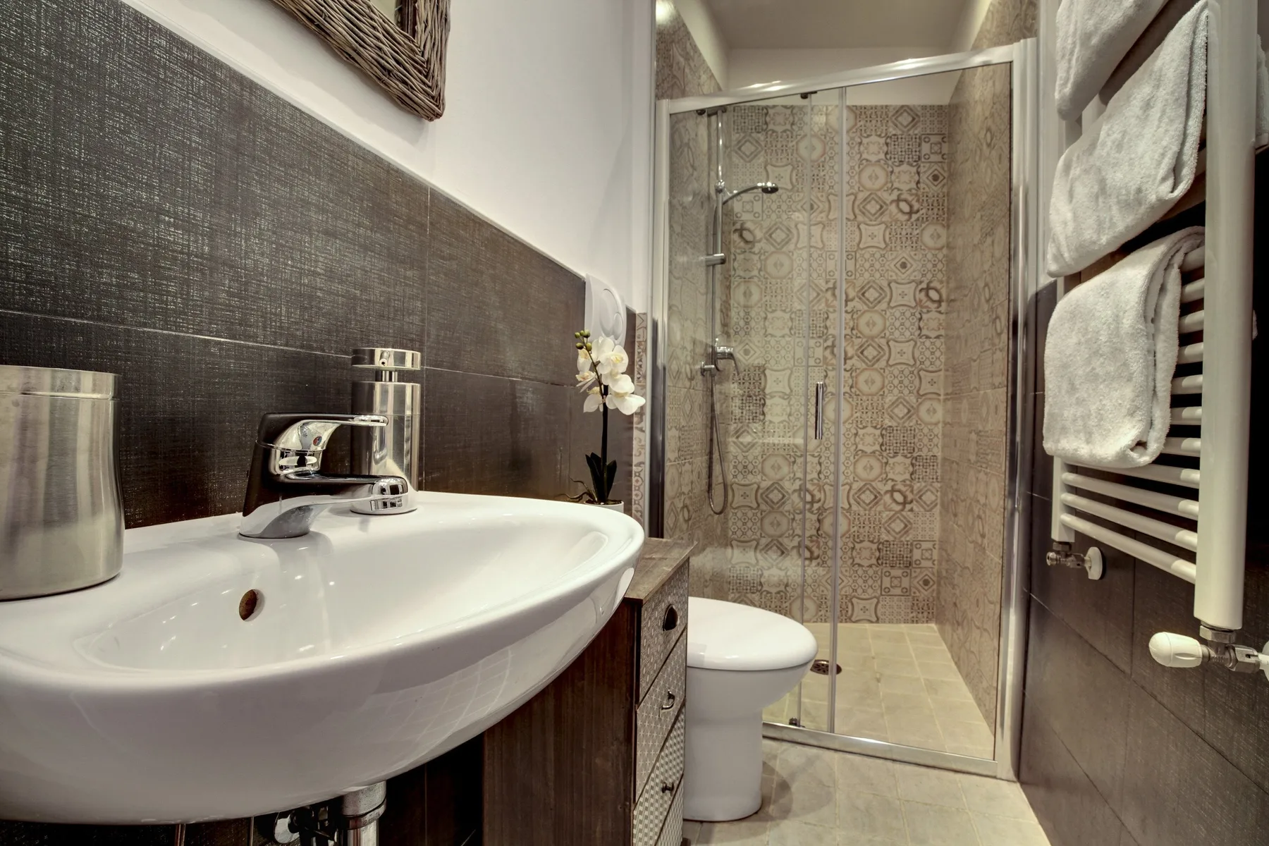 A bathroom with a sink in the foreground and a glass shower enclosure.