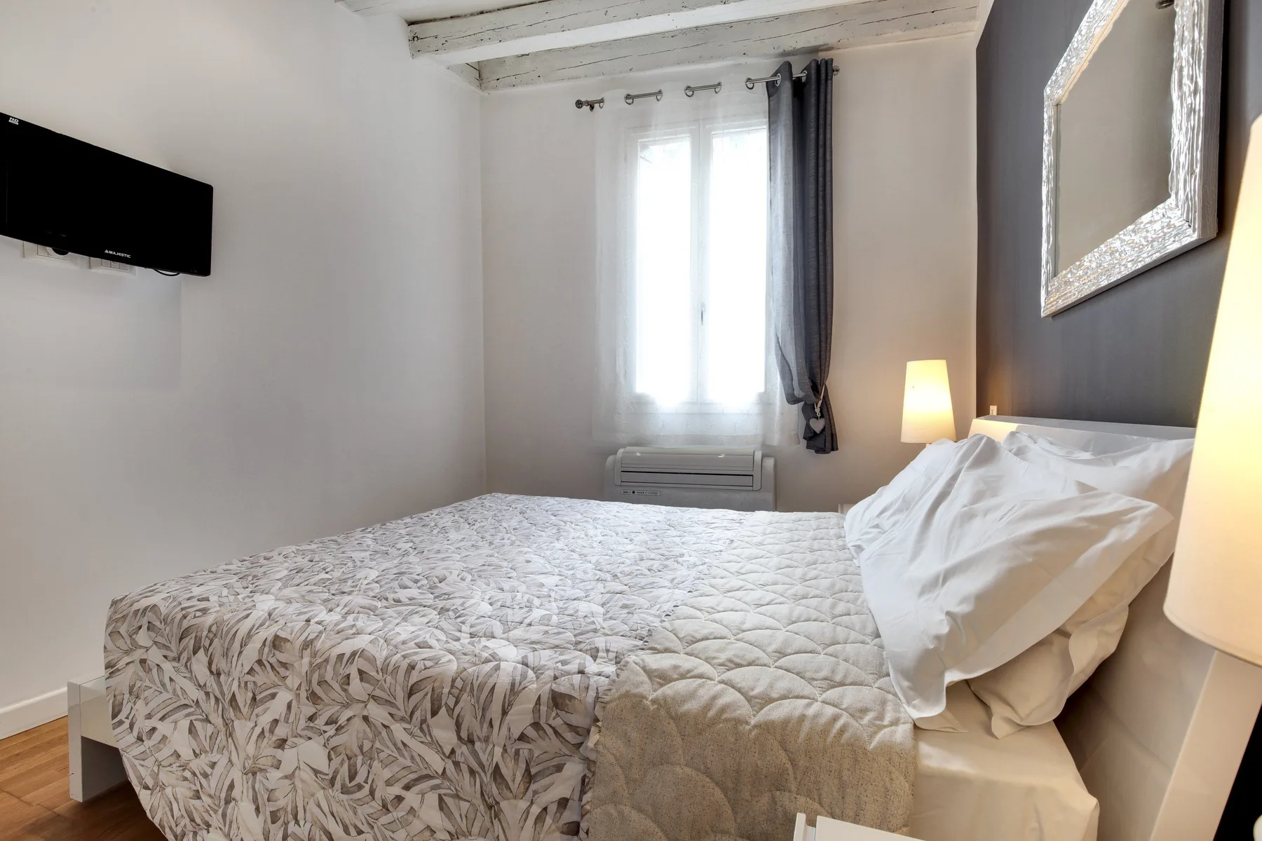 A bedroom with a large bed beneath a bright window.