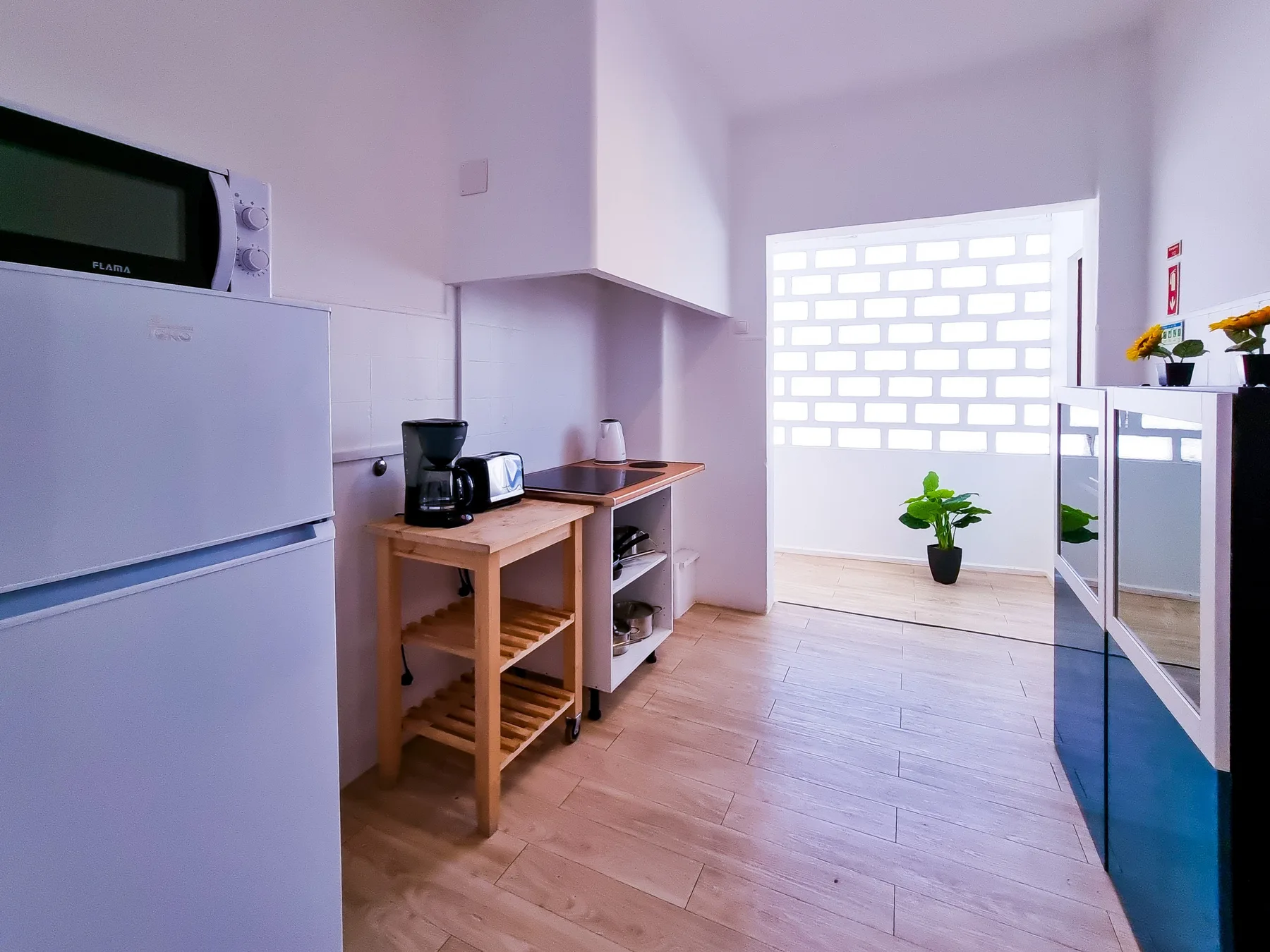 Una pequeña cocina con refrigerador, microondas y una encimera.