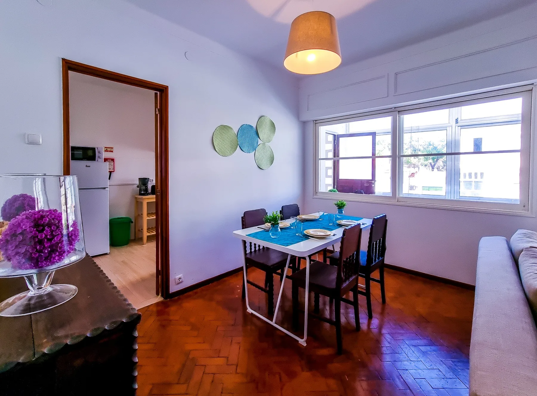 Un comedor con una mesa junto a amplias ventanas y una zona de estar.