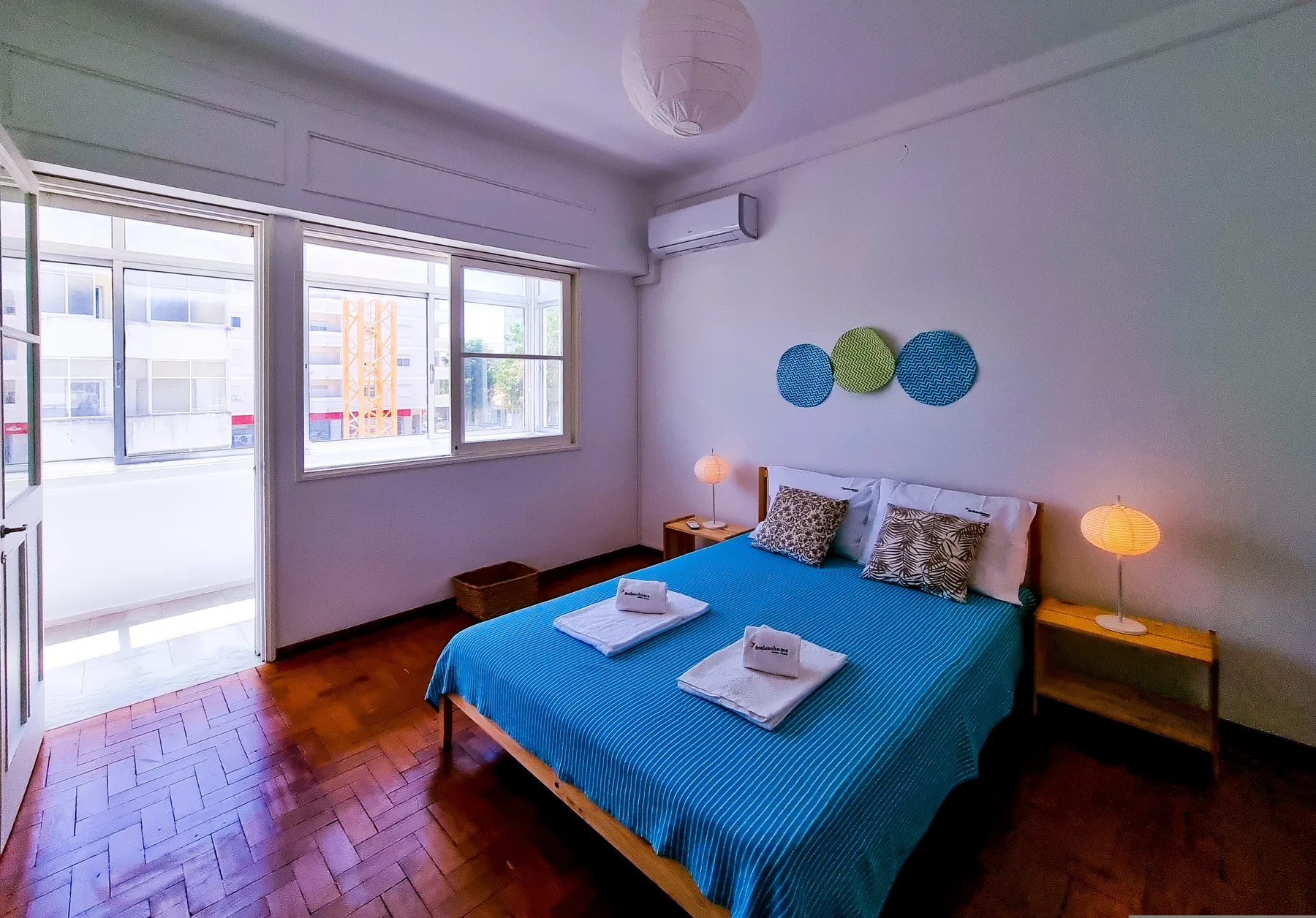 Un dormitorio con una cama cubierta de azul y grandes ventanas.