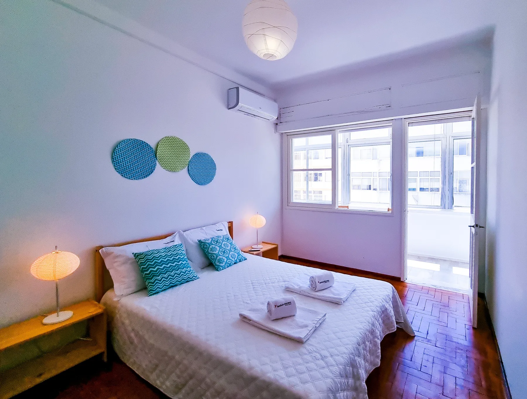 Dormitorio con una cama, mesillas de noche y ventanas que dan a un balcón.
