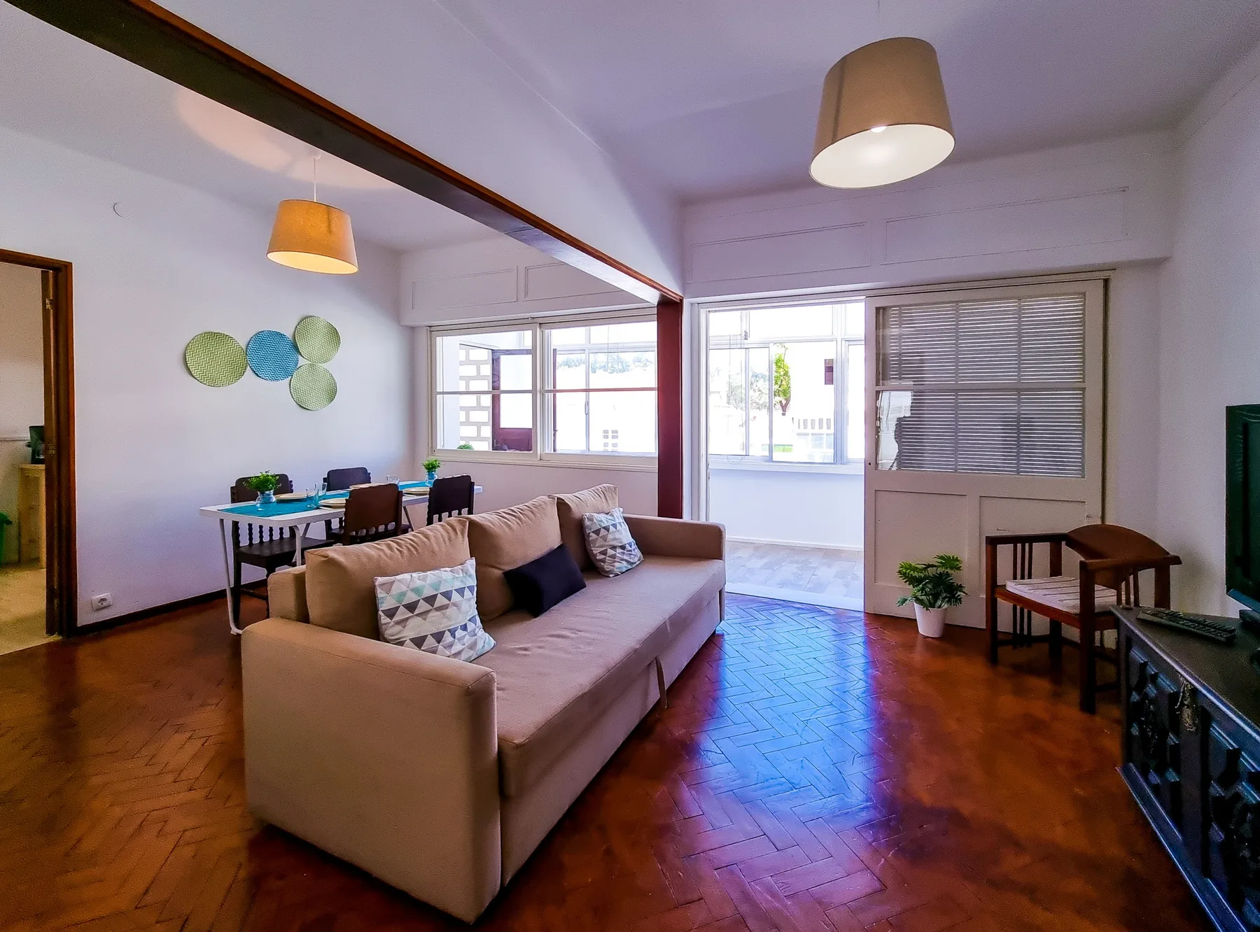 Una sala de estar con asientos y una mesa de comedor junto a las ventanas.