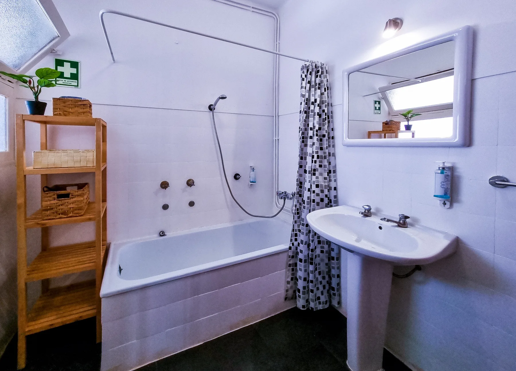 Un baño con bañera, ducha de mano y lavabo.
