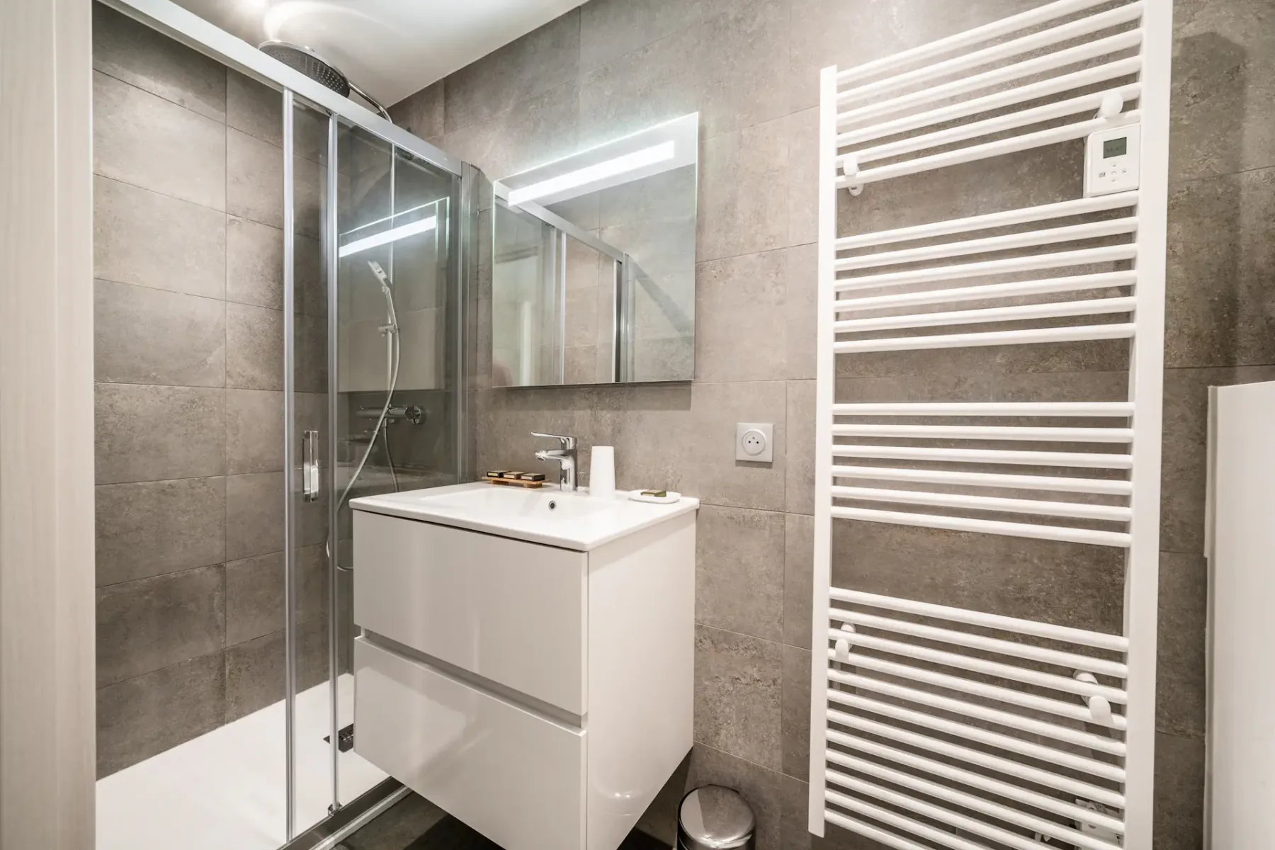 Modern bedroom and bathroom with wooden accents; the bathroom has a bathtub and a large window with a mountain view.