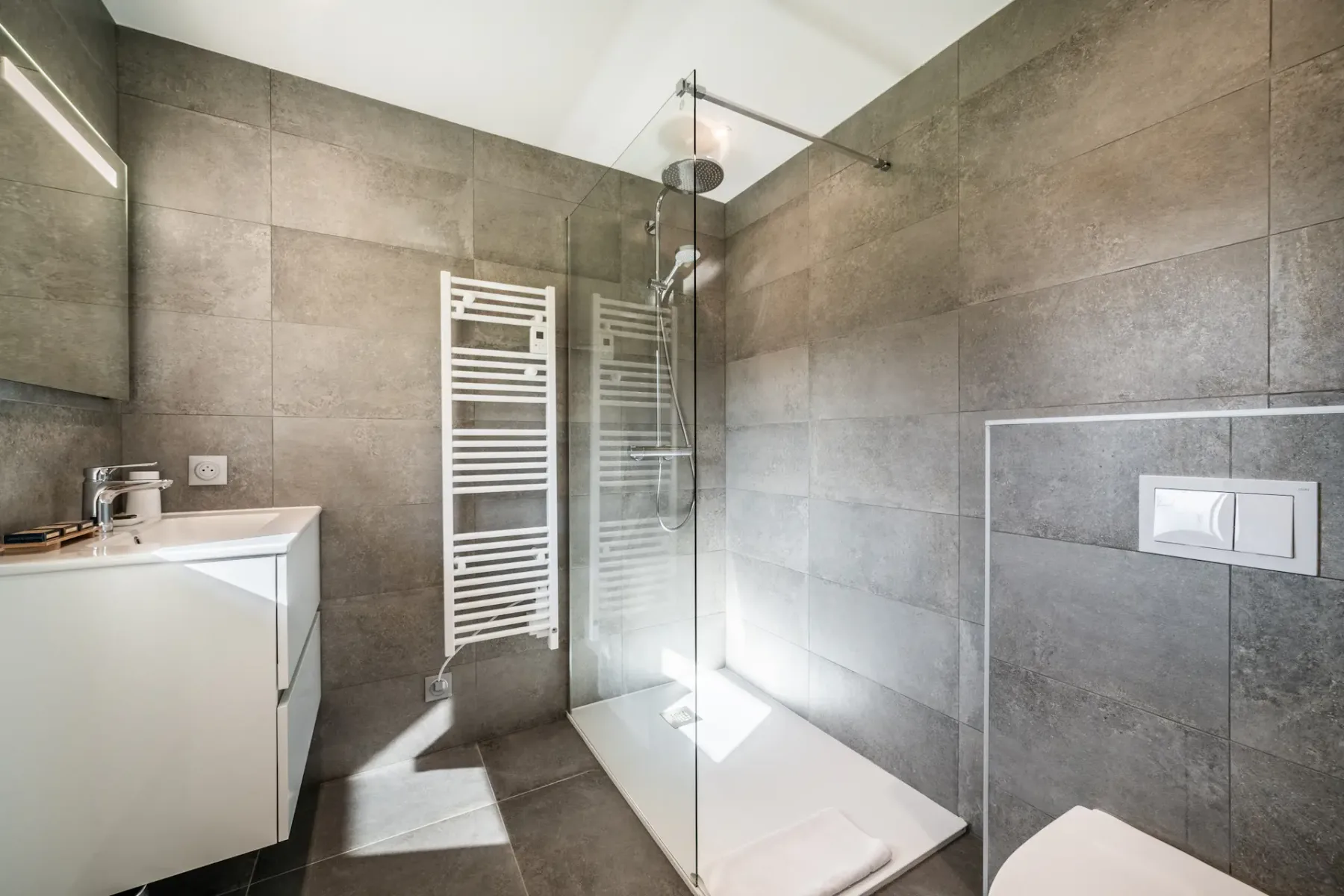 Modern bedroom and bathroom with wooden accents; the bathroom has a bathtub and a large window with a mountain view.