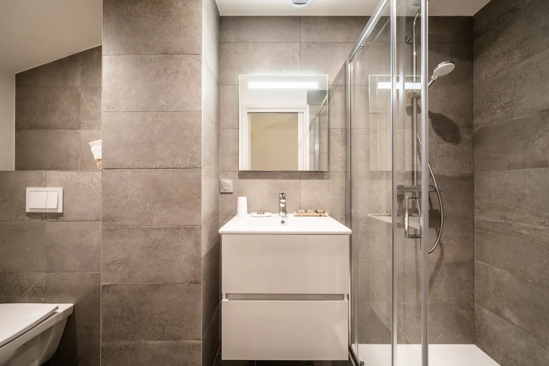 Modern bedroom and bathroom with wooden accents; the bathroom has a bathtub and a large window with a mountain view.