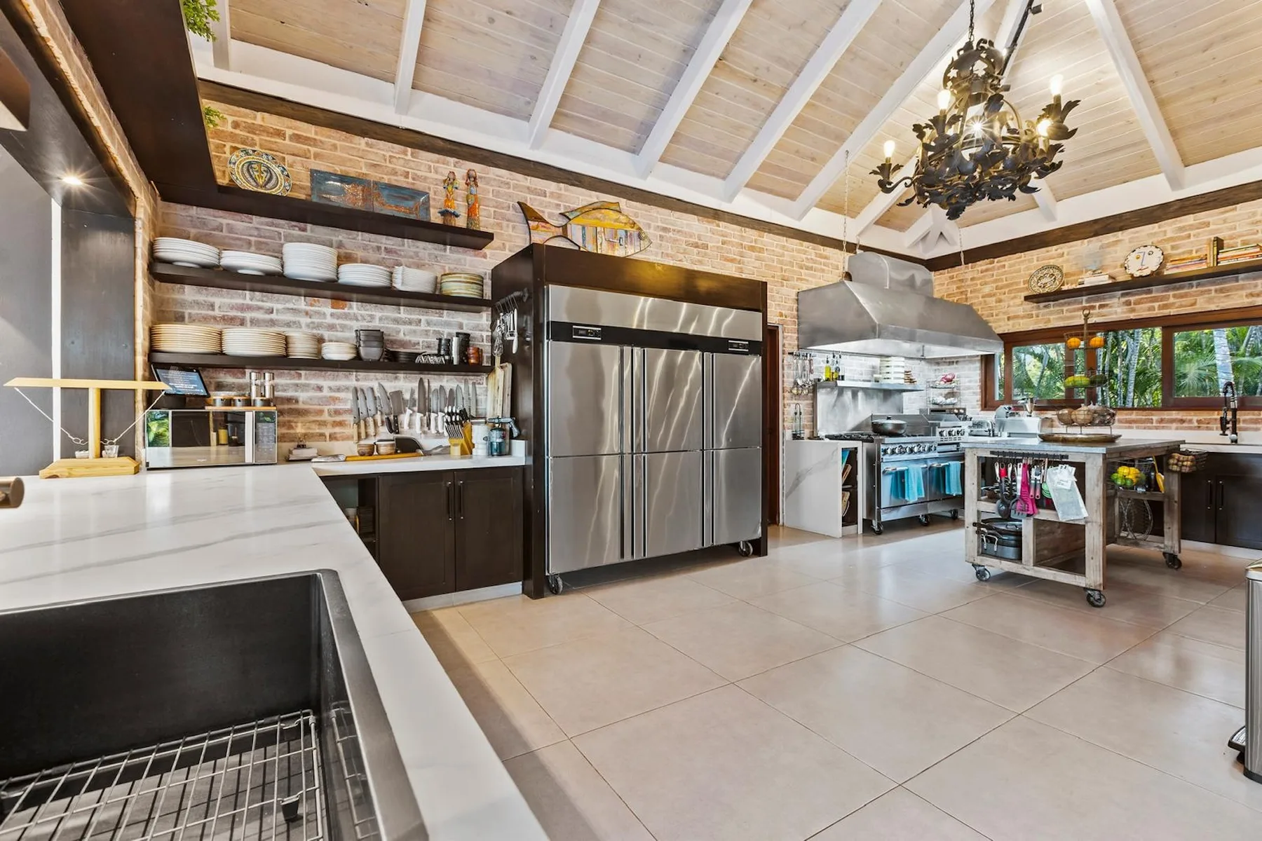 Una cocina amplia con un refrigerador grande, estantes abiertos y una zona de trabajo central.