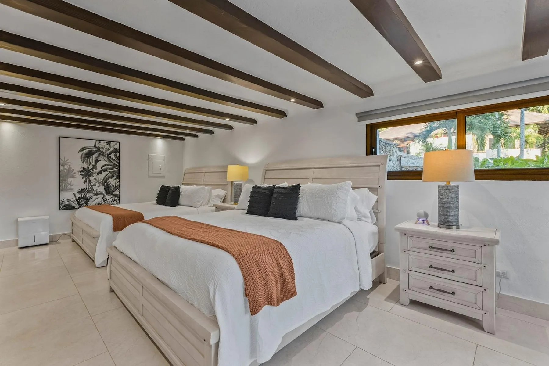Un dormitorio con dos camas, ropa de cama blanca y vigas de madera en el techo.