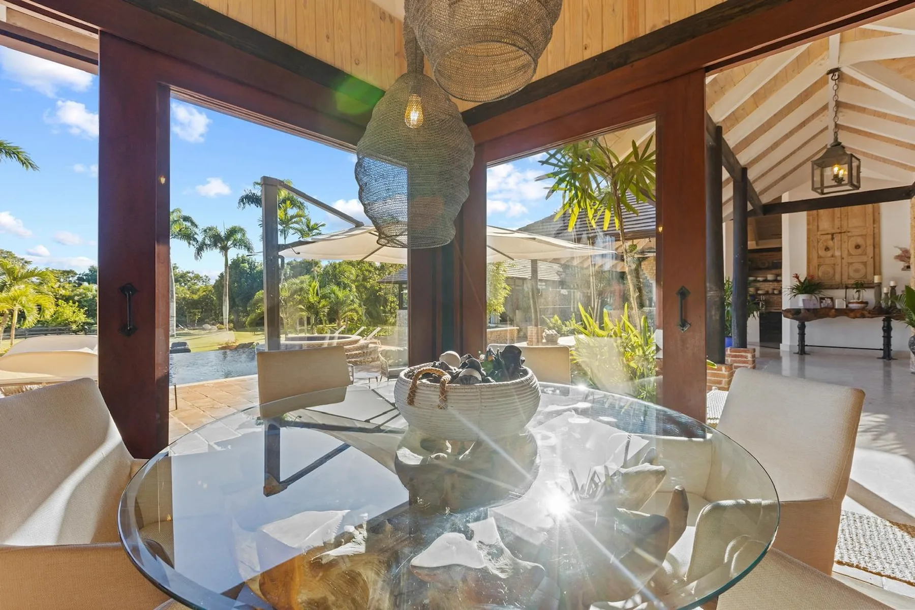 Comedor con una mesa de vidrio y vistas al jardín a través de las puertas abiertas.