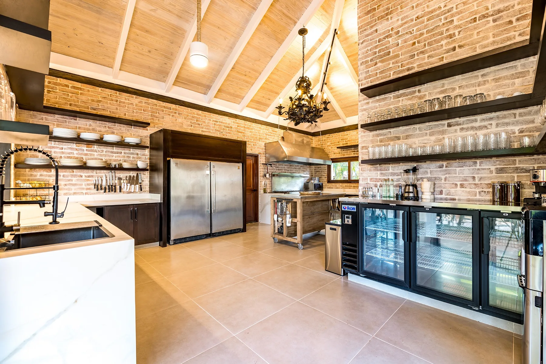 Una amplia cocina y zona de bar con paredes de ladrillo y techo alto de madera.